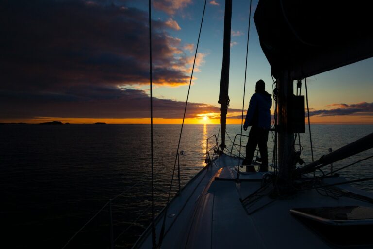 a person standing on the deck of a boat at sunset, segelschein